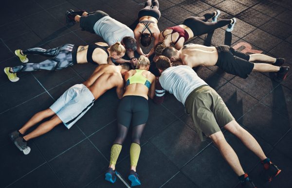 Fit young people focused on planking in a circle in a gym